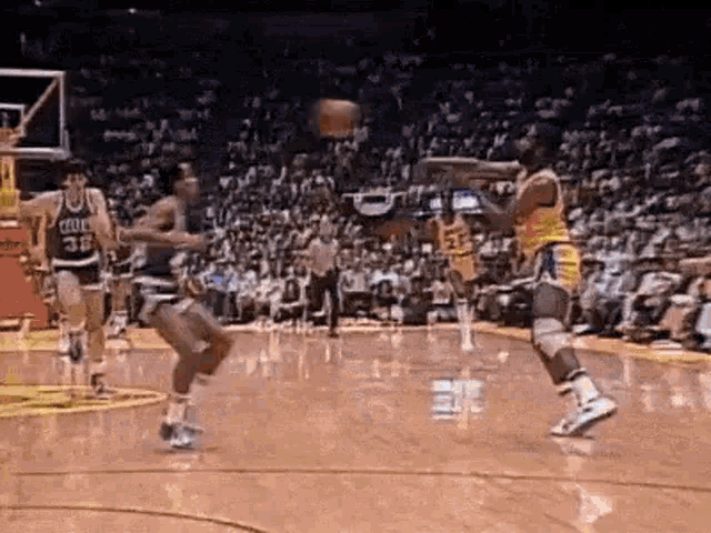 a group of basketball players are playing basketball on a court in front of a crowd . a group of basketball players are playing basketball on a court in front of a crowd .