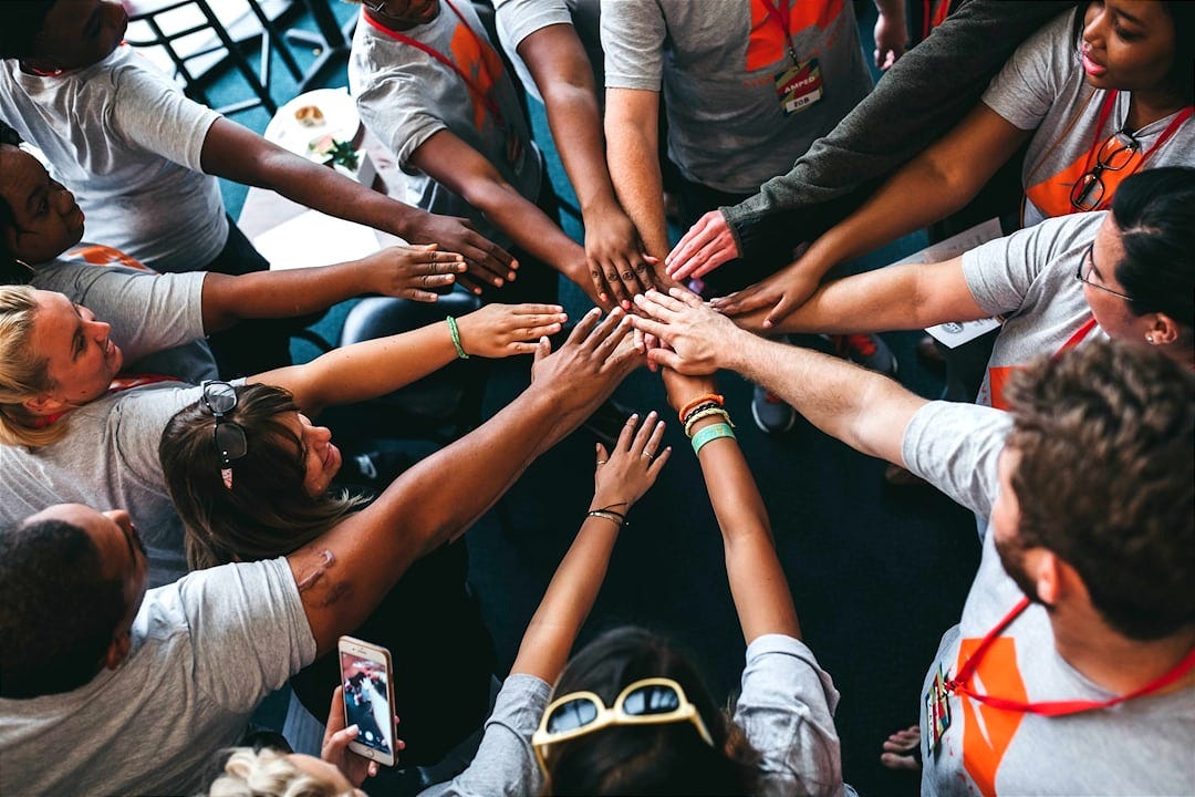 people with hands gathered in the middle people with hands gathered in the middle