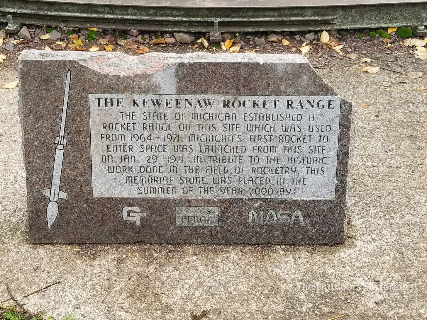 A rock monument engraved with information about the Keweenaw Rocket Range.