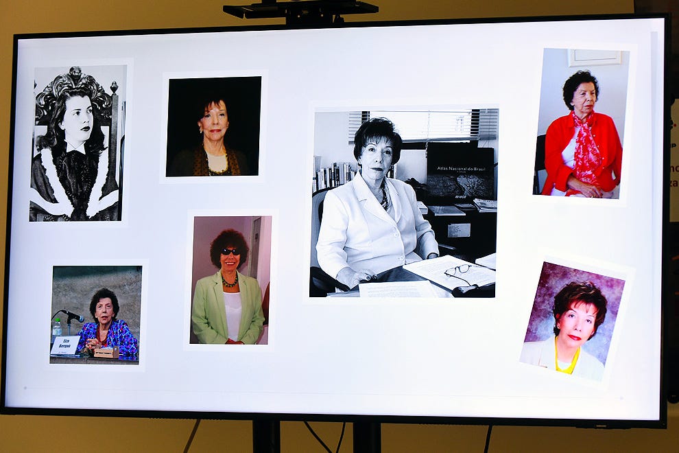 Painel exibido em tela com sete fotografias de pessoas em diferentes contextos: no canto superior esquerdo, retrato em preto e branco de pessoa com cabelo volumoso e roupas ornamentadas; abaixo, pessoa sentada em mesa com microfone; ao centro superior, pessoa com cabelo castanho em fundo escuro; no centro, pessoa em blusa branca sentada à mesa com papéis e ambiente de escritório ao fundo; no canto superior direito, pessoa em blusa vermelha com lenço rosa; no canto inferior direito, pessoa com cabelo preto curto em fundo roxo; e ao centro-esquerda inferior, pessoa em blusa estampada azul com óculos escuros em fundo rosa claro.