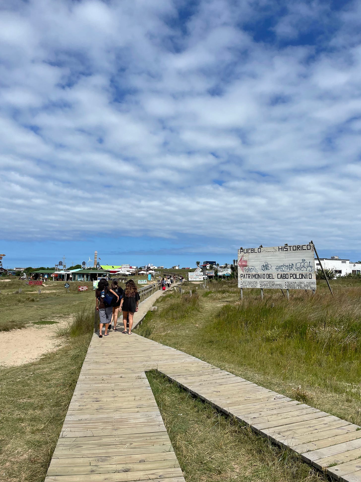 a wooden walkway surrounded by dirt roads that leads in a town