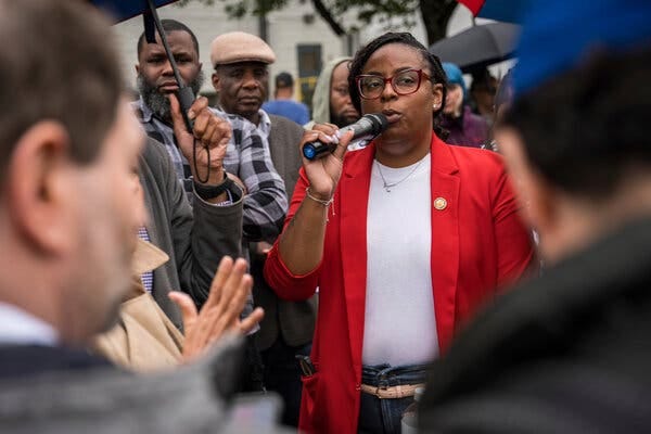 Representative LaMonica McIver speaking into a microphone as a crowd surrounds her. Representative LaMonica McIver speaking into a microphone as a crowd surrounds her.