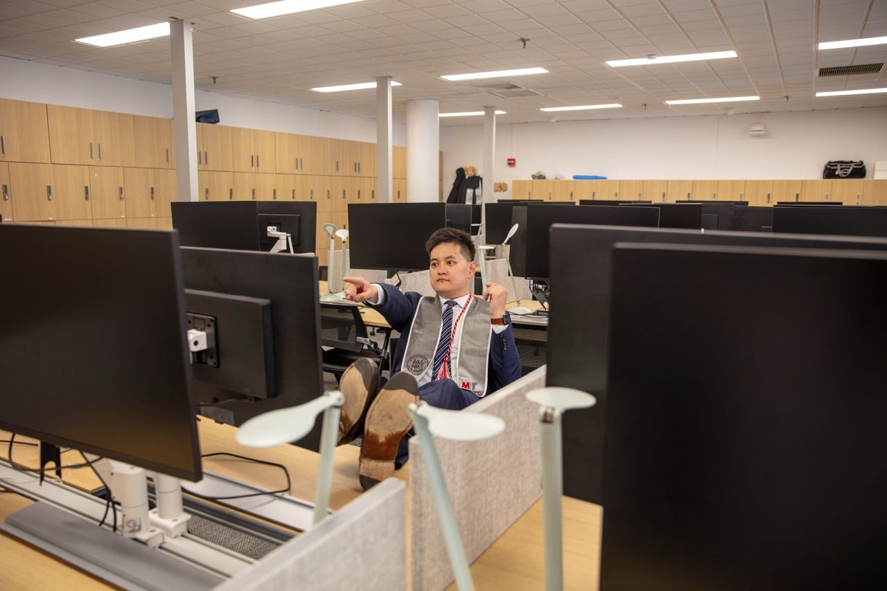 Junru in a suit and LGO graduation stole relaxing with his feet on a desk in the LGO student lounge Junru in a suit and LGO graduation stole relaxing with his feet on a desk in the LGO student lounge
