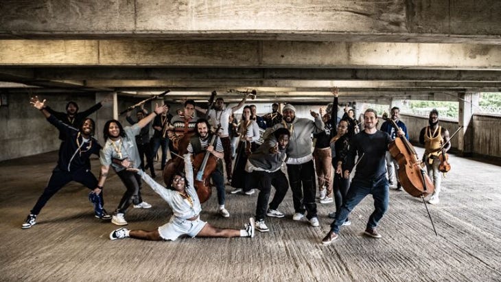 The Multi-Story Orchestra posing with their instruments in a multi-storey car park