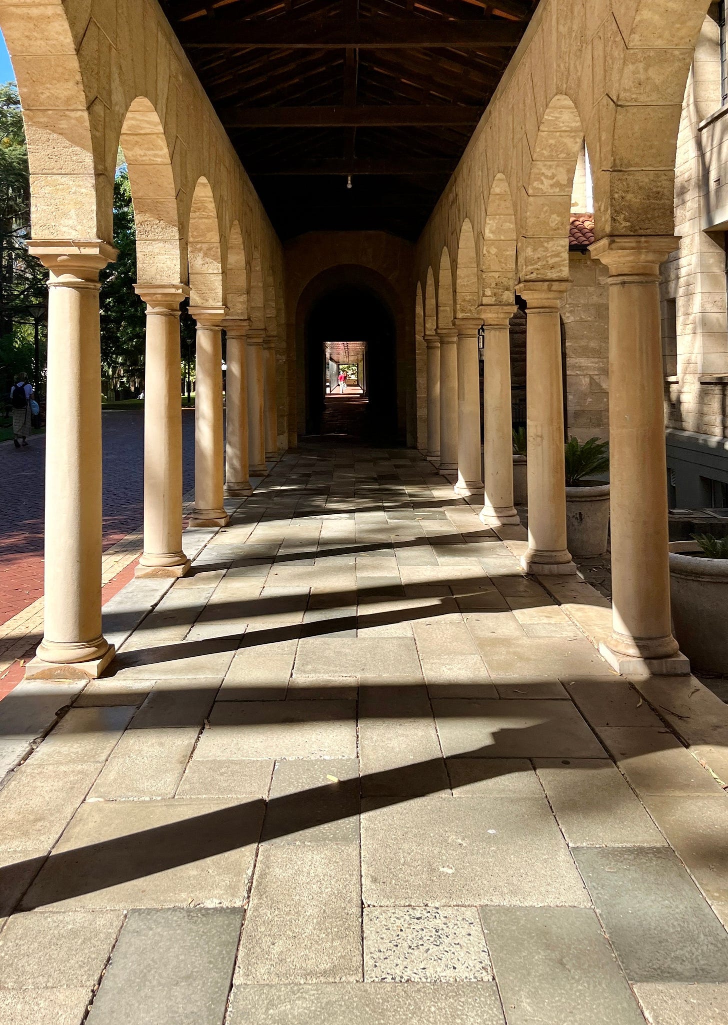Symmetrical stone archway corridor with shadows at a university in Crawley, WA.