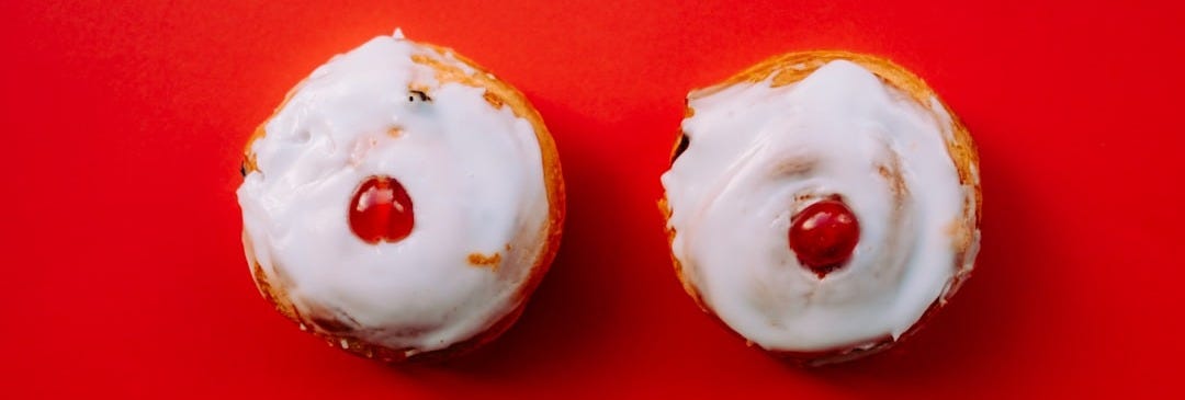 two white frosted cupcakes with cherry toppings