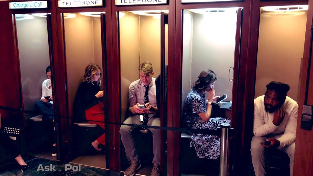 A group of reporters sit in historic wooden phone booths, but they're all busy typing on their phones. © www.askapol.com 