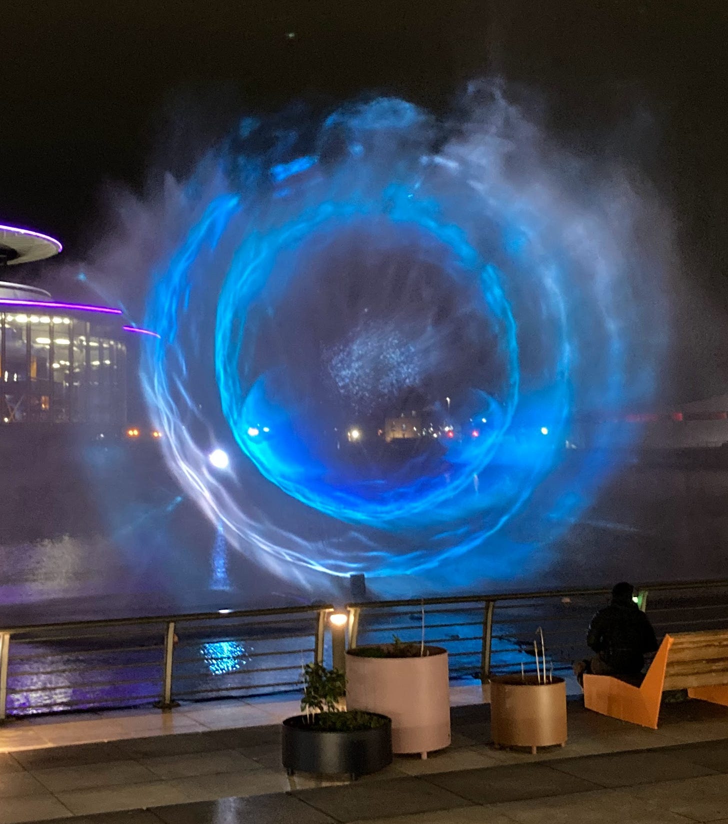 Water and lights display over Salford Quay. Light projection onto a continuous spray of water creates the illusion of an otherworldly portal suspended in mid-air. 