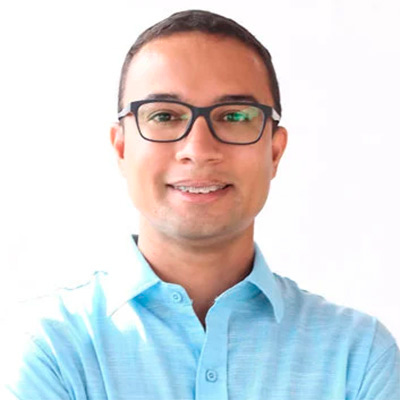 Homem de cabelos e olhos pretos, usa óculos e camisa azul. Homem de cabelos e olhos pretos, usa óculos e camisa azul.