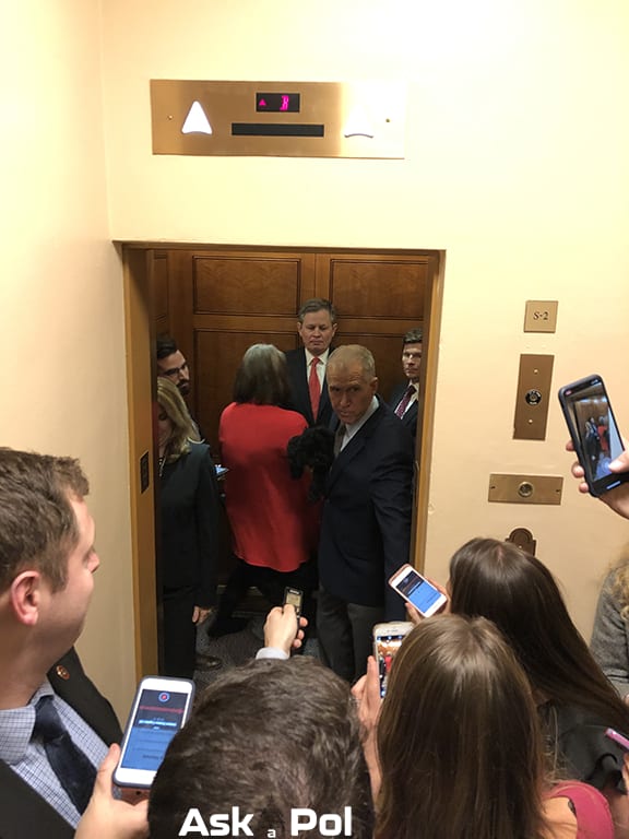 Reporters stand outside an elevator recording a politician's responses as he boards an elevator. Photo © www.askapoldrugs.com Reporters stand outside an elevator recording a politician's responses as he boards an elevator. Photo © www.askapoldrugs.com