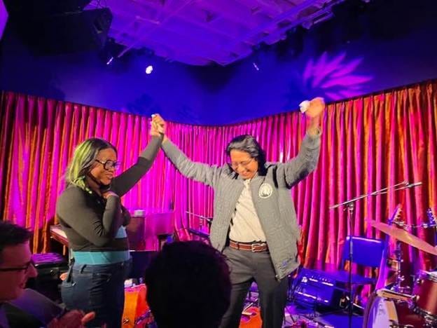 A person and person holding hands in front of a stage

AI-generated content may be incorrect.