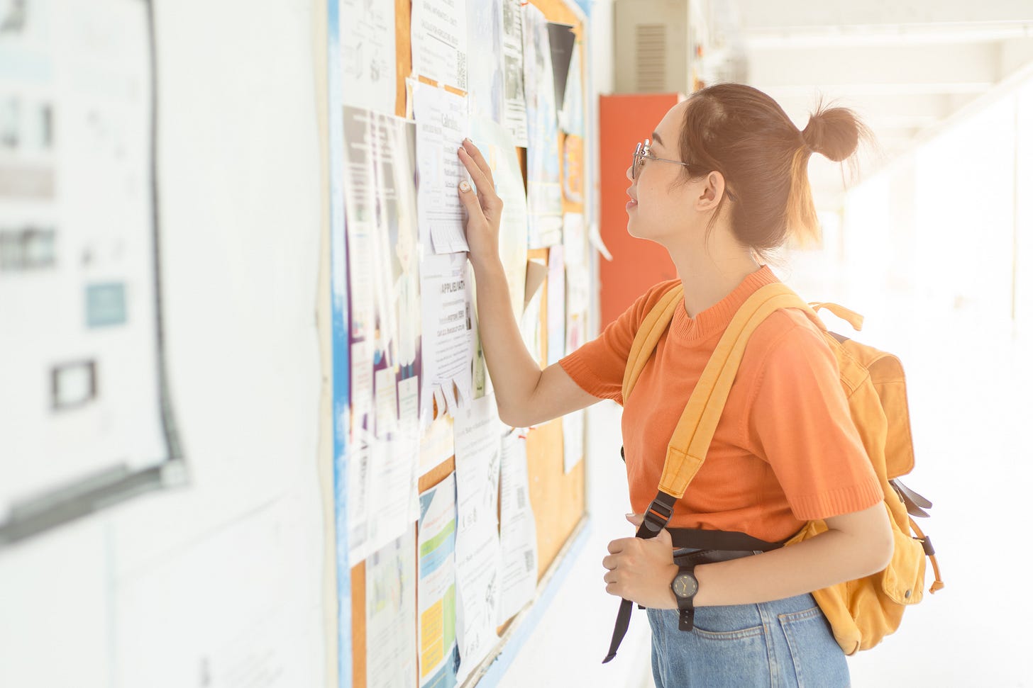 Student looking at help wanted posters on a bulletin board