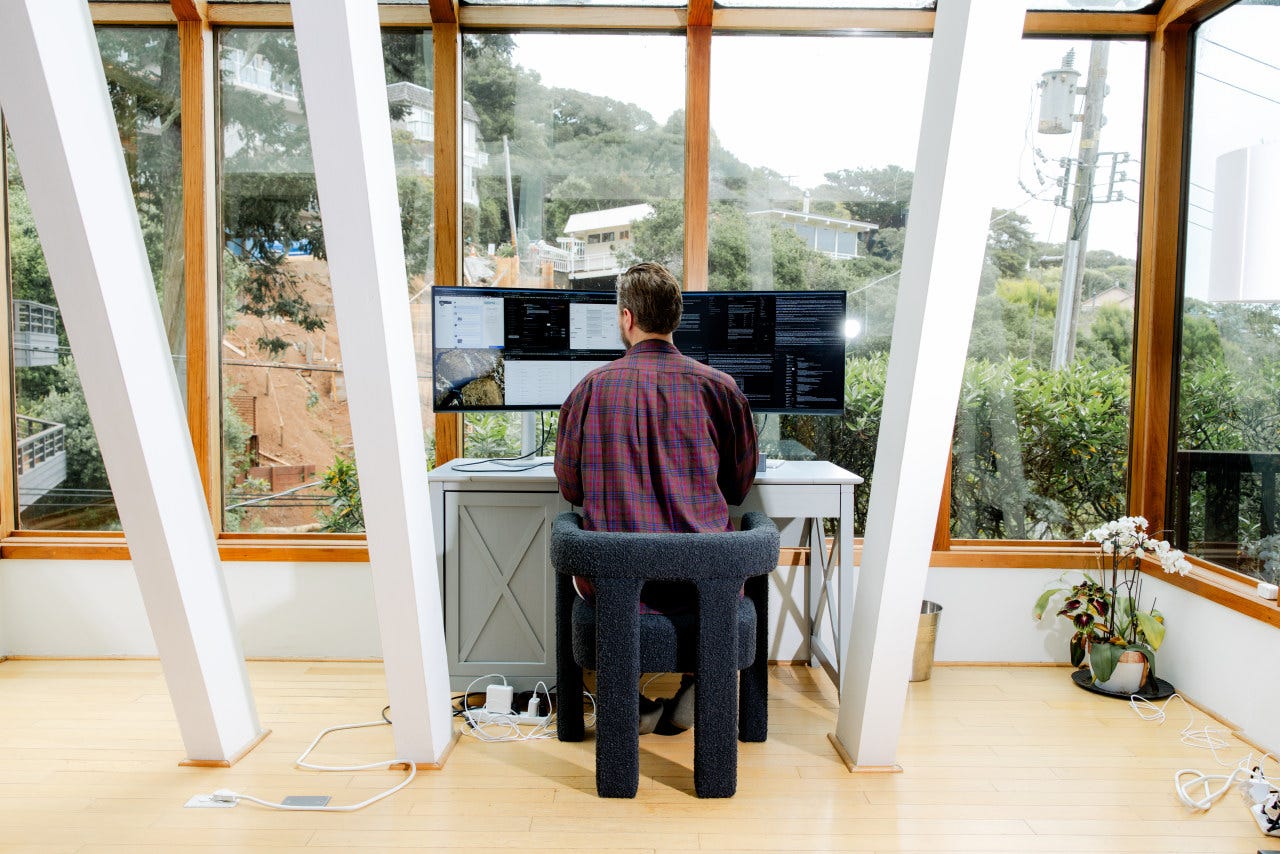 Ben Broca at his home office with multiple monitors overlooking a green landscape. Ben Broca at his home office with multiple monitors overlooking a green landscape.