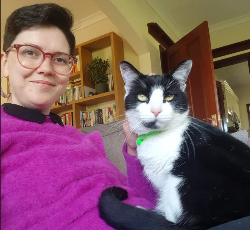 A photo of Janelle and Victor. Victor is a black and white tuxedo cat with long white whiskers, a large white bib, and a black spot on the right side of his chin. A photo of Janelle and Victor. Victor is a black and white tuxedo cat with long white whiskers, a large white bib, and a black spot on the right side of his chin.