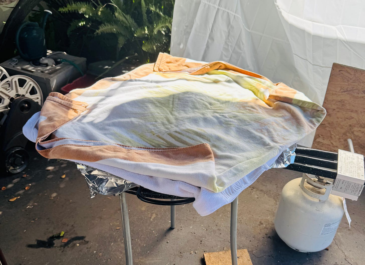 A pan of cooked paella is covered in foil and towels to steam