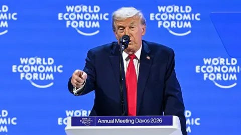 Getty Images Donald Trump delivers a speech from a lectern at the World Economic Forum in Davos wearing a navy suit, red tie and a US flag pinned to his suit. Getty Images Donald Trump delivers a speech from a lectern at the World Economic Forum in Davos wearing a navy suit, red tie and a US flag pinned to his suit.