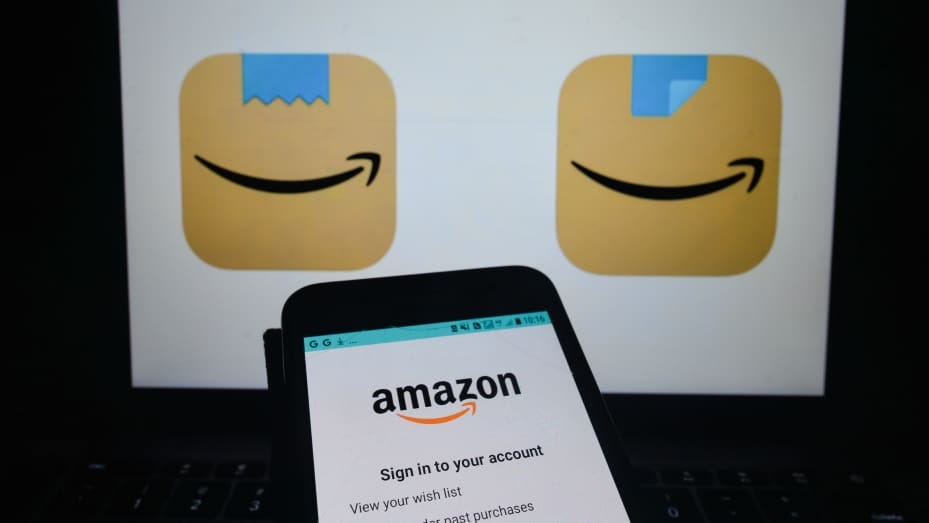An illustrative image of Amazon Shopping app seen on a mobile phone screen in front of an old (L) and a new (R) Amazon Shopping app icons displayed on a screen. Amazon has quietly changed its new Amazon Shopping app icon, replacing the blue ribbon on top An illustrative image of Amazon Shopping app seen on a mobile phone screen in front of an old (L) and a new (R) Amazon Shopping app icons displayed on a screen. Amazon has quietly changed its new Amazon Shopping app icon, replacing the blue ribbon on top