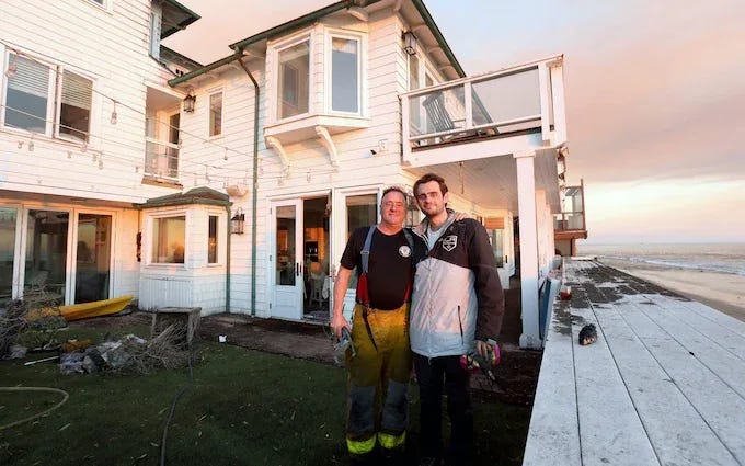 Brain surgeon Chester Griffiths stands with his son Chester jnr in front of the homes they saved Brain surgeon Chester Griffiths stands with his son Chester jnr in front of the homes they saved