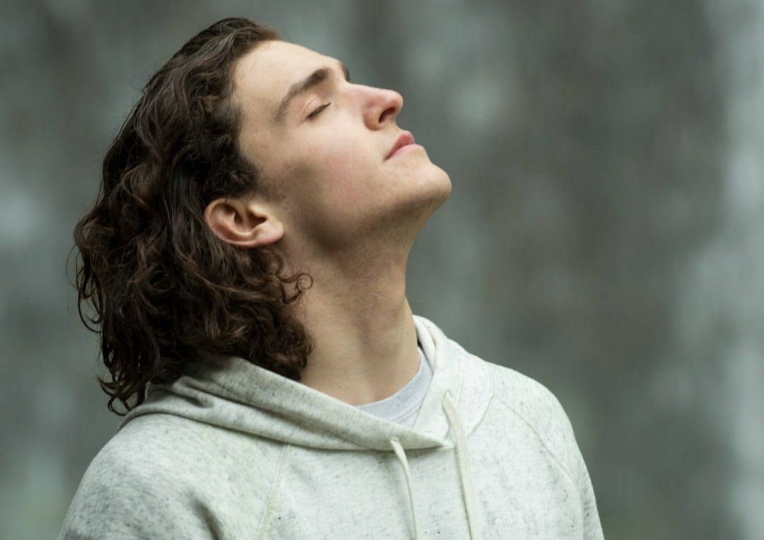 man in gray pullover hoodie closed eyes while heads up