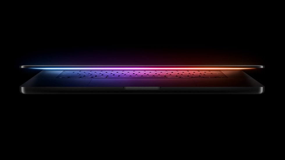 An almost shut MacBook Pro emits a colorful glowing light. An almost shut MacBook Pro emits a colorful glowing light.