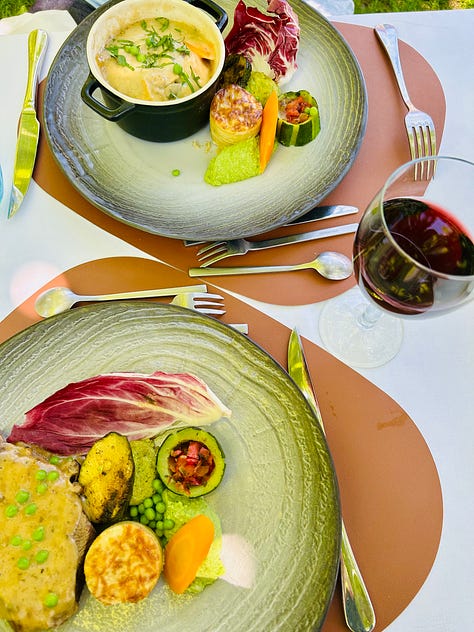 Different scenes from summer in France. A green garden with bench; a river with a table set for lunch in the water; a father and his kids; a classic red and white checked French tablecloth: Karen Bussen at home in her gardening apron; lunch plates from the Moulin de Flagy; and scenes of sunset and flowers in France