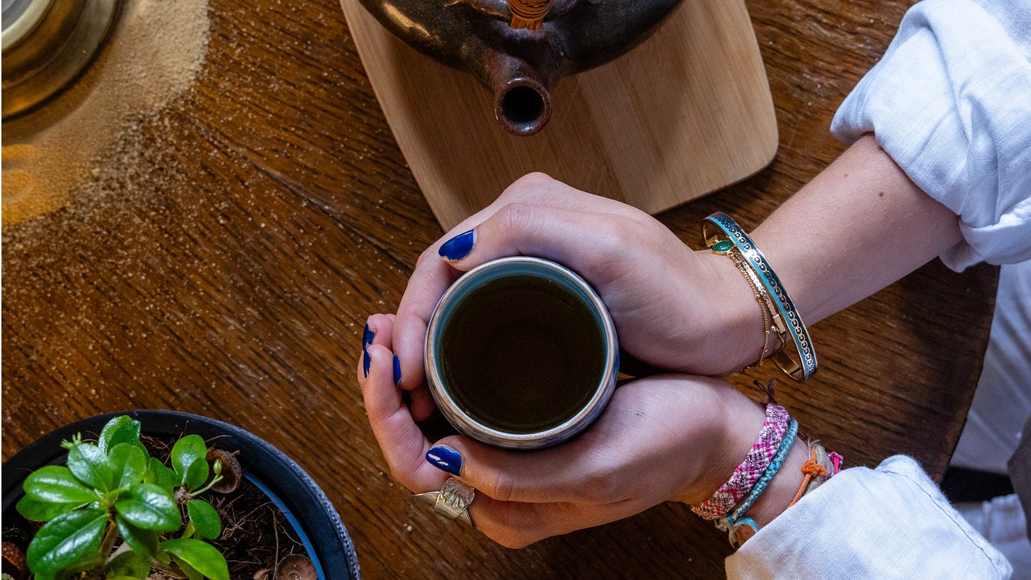 A woman wearing ethnic bangles on her wrists nurses a warming cup of herbal tea.