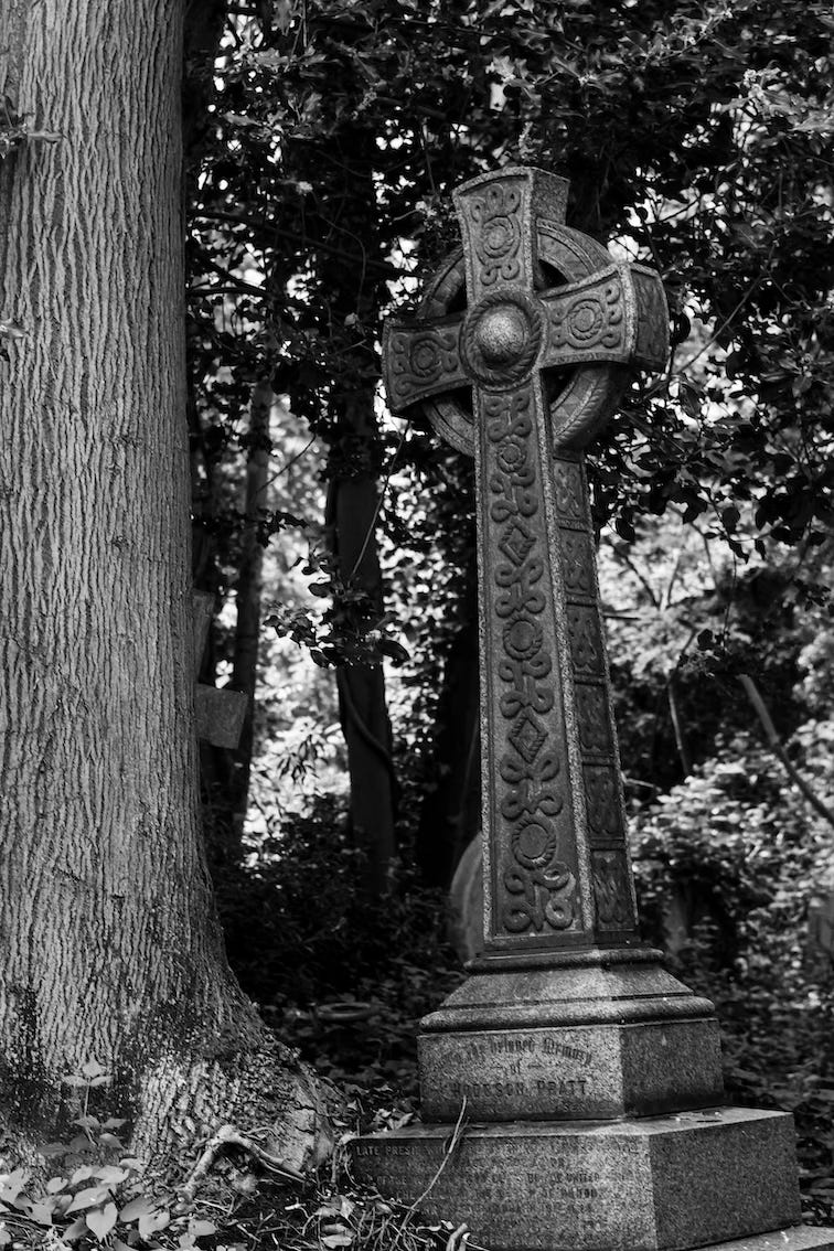 black and white image of a Celtic cross in a forest