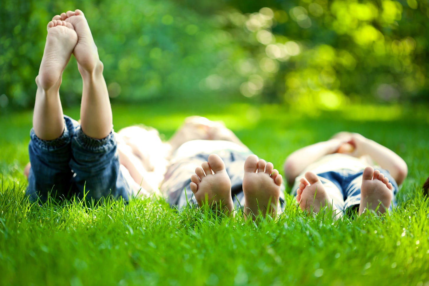 Kids laying in the grass barefooted on a sunny day