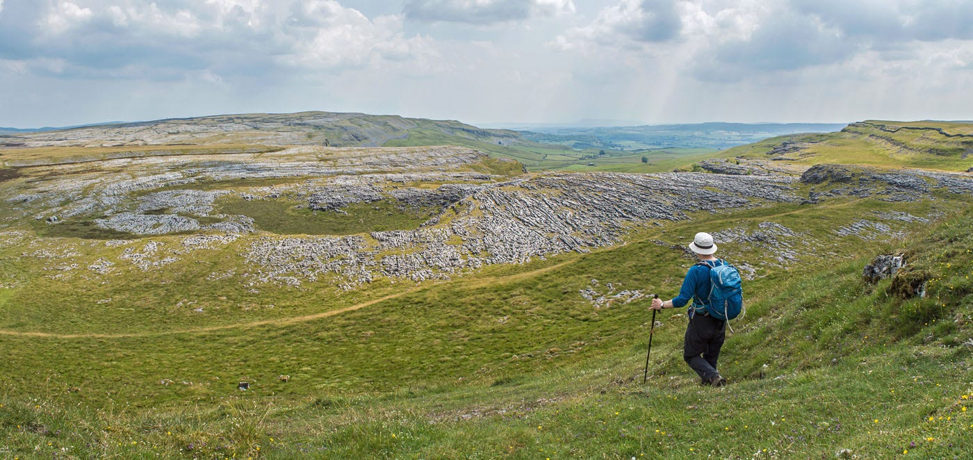me in white hat heading towards some limestone pavement