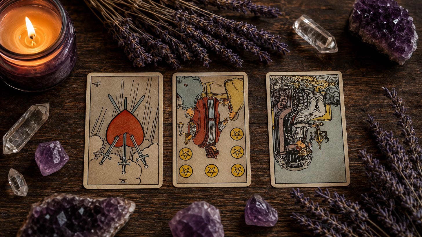 A three-card tarot spread laid out on a wooden table between a lit candle and clear quartz crystals.