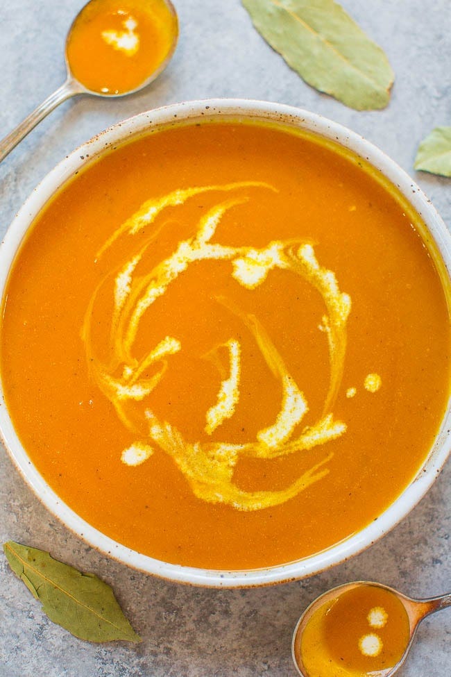 A bowl of creamy pumpkin soup with two spoons on the side. A bowl of creamy pumpkin soup with two spoons on the side.