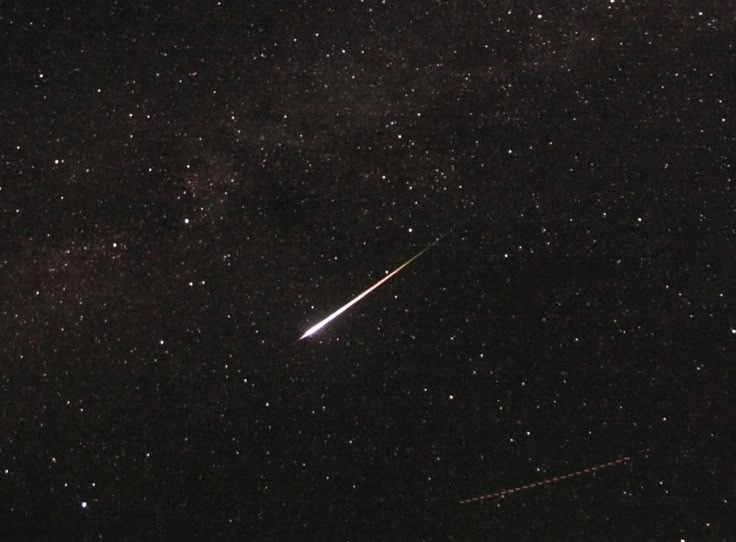 This may contain: an airplane flying through the night sky with stars in the background and a shooting star above it