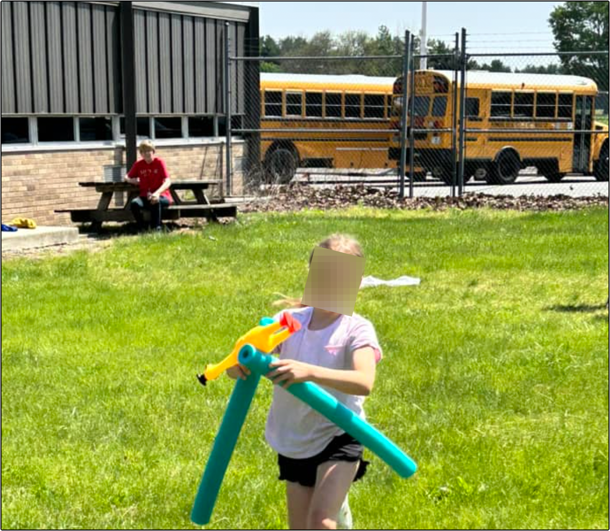 With public school buses visible in the background, LifeWise Elmwood student plays on public school property at Elmwood Local School District for Bible study. 