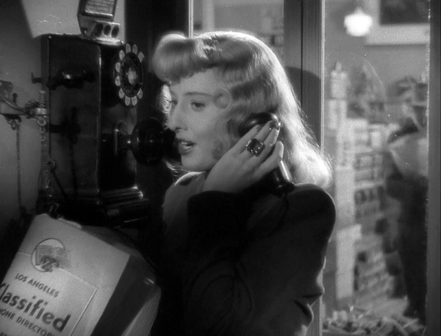 Barbara Stanwyck takes a call in a phone booth in Double Indemnity (1944)
