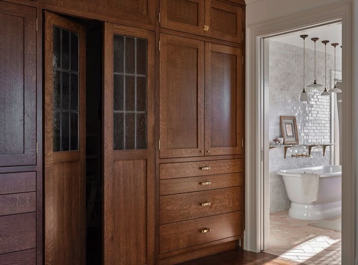 This may contain: a bathroom with wooden cabinets and a white tub in it's centerpieces