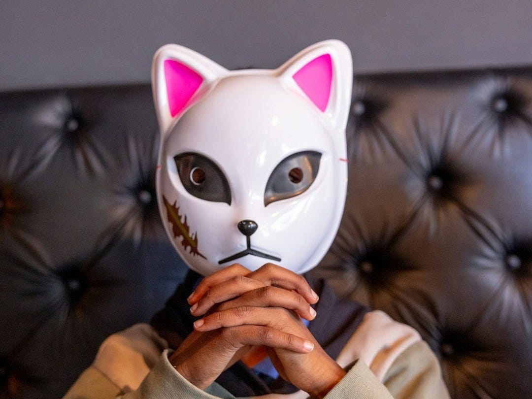 A person is wearing a white cat mask.