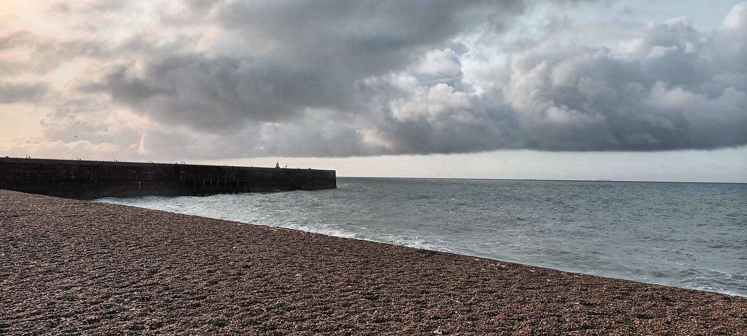 Shingle beach with grey skies over head and grey seas