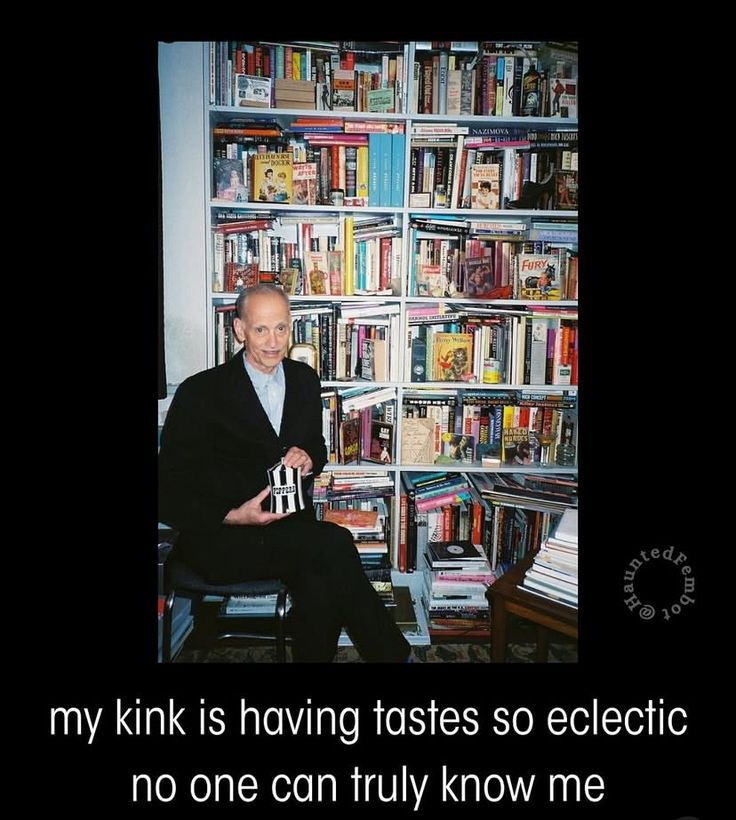 This may contain: a man sitting on a chair in front of a bookshelf filled with books