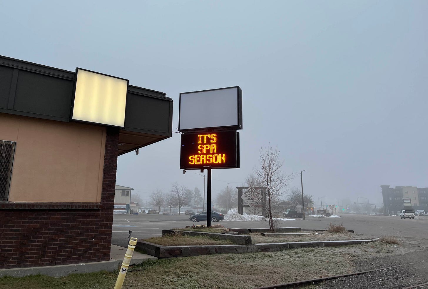 sign reading it's spa season on gray foggy snowless day