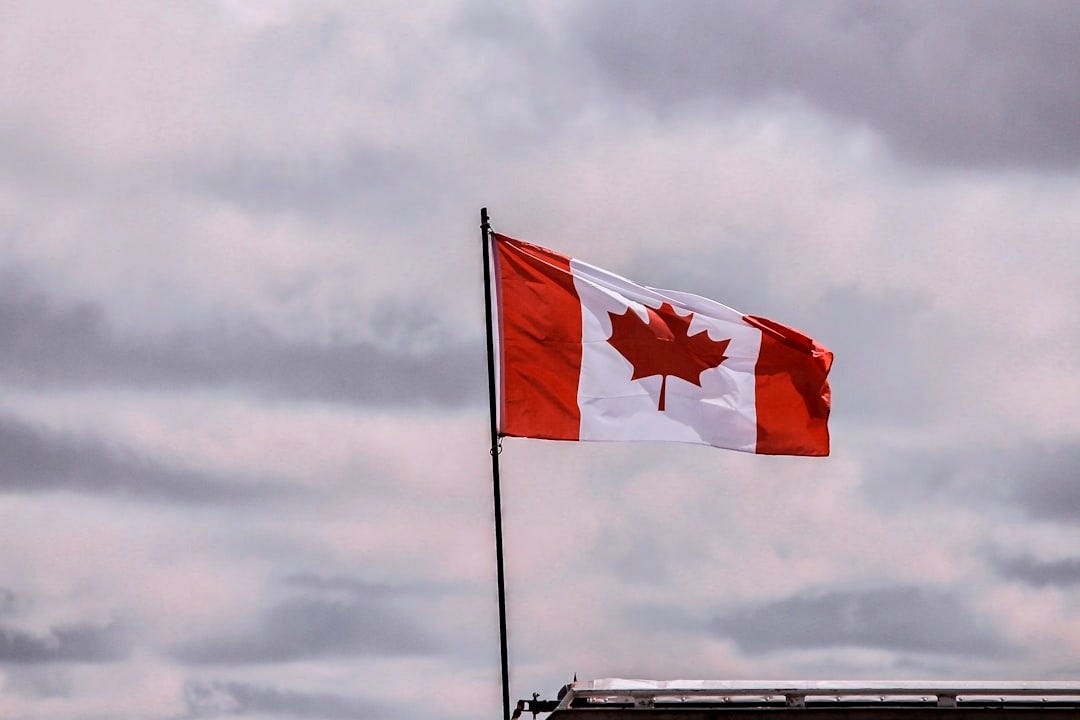 a canadian flag flying in the wind on a cloudy day