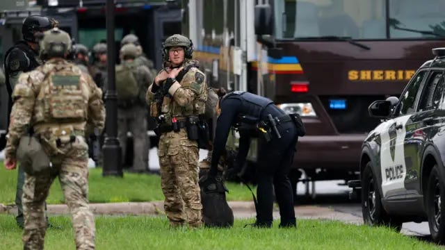 Police officers, some wearing military-style camouflage, and vehicles