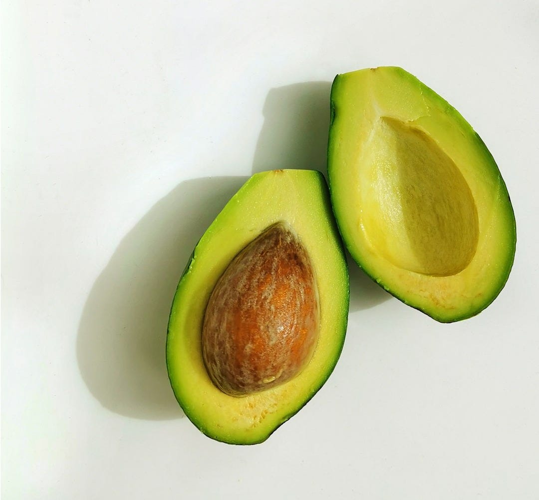 an avocado cut in half on a white surface an avocado cut in half on a white surface