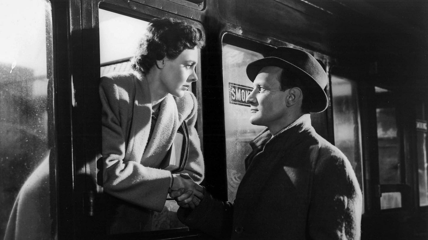 Celia Johnson and Trevor Howard in Brief Encounter (1945), sharing a final goodbye through a train window. She leans out in a wool coat, clasping his hand, their faces locked in quiet agony as the train prepares to depart. Celia Johnson and Trevor Howard in Brief Encounter (1945), sharing a final goodbye through a train window. She leans out in a wool coat, clasping his hand, their faces locked in quiet agony as the train prepares to depart.
