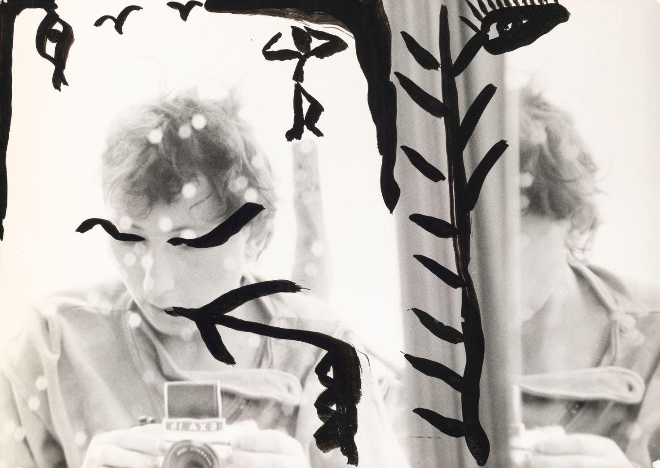 A self-portrait by Gabriele Stötzer, painted with black patterns, capturing herself in the mirror with an analog camera. A self-portrait by Gabriele Stötzer, painted with black patterns, capturing herself in the mirror with an analog camera.