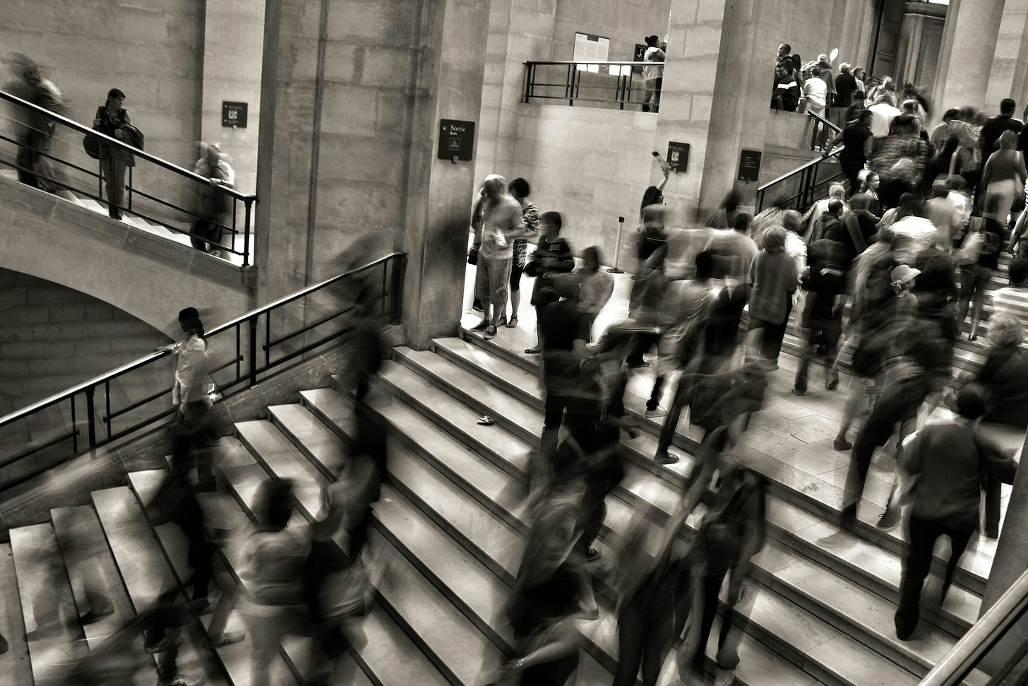 Blurred crowd moving through a public building, illustrating constant activity, routine work, and the high volume of repetitive tasks before automation. Blurred crowd moving through a public building, illustrating constant activity, routine work, and the high volume of repetitive tasks before automation.