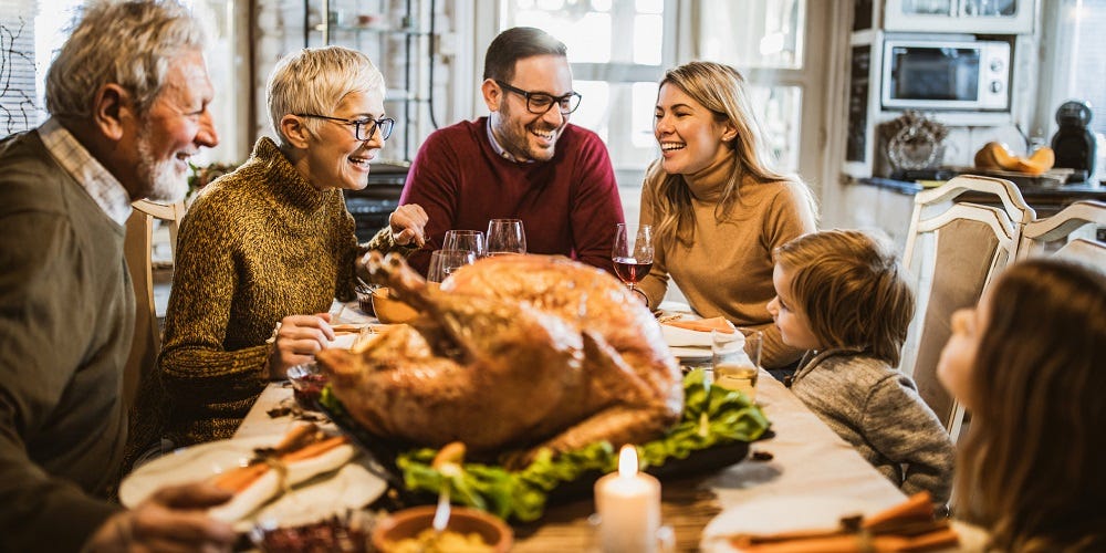 A group of people around a table with a turkey

Description automatically generated