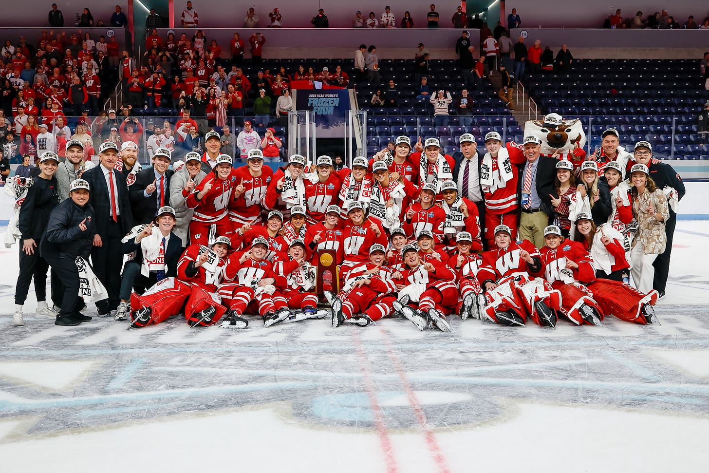 the Wisconsin women's hockey team poses at center ice for a team photo after winning the NCAA Tournament