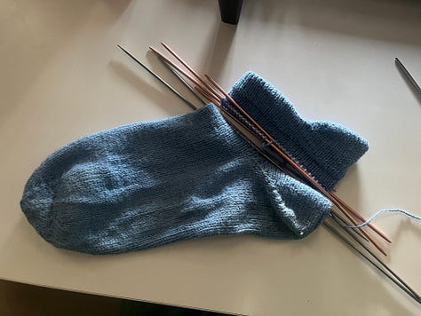 Photos showing the process of knitting and attaching new cuffs to a pair of blue handknit socks