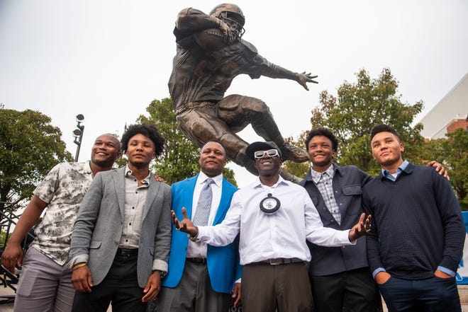 Barry Sanders, center left, poses for a photo with Flavor Flav, center right, and Sanders' four sons, in front of a statue in his honor after it was unveiled outside of Ford Field on Saturday, Sept. 16, 2023.
