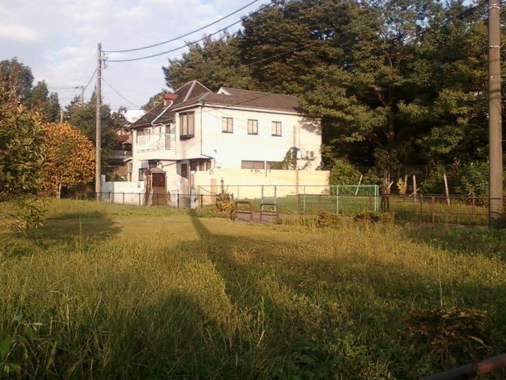 A white suburban duplex surrounded by trees and grass.